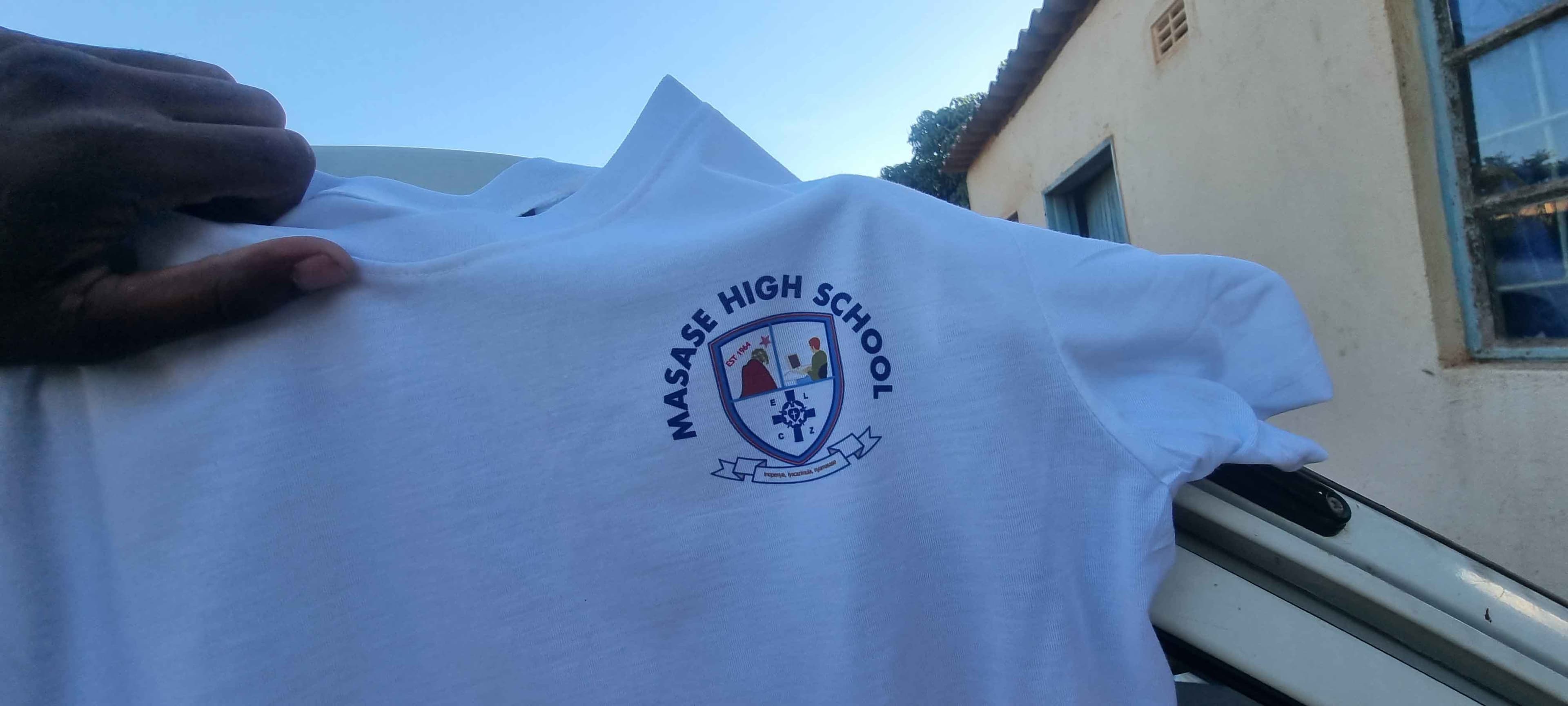 A white shirt printed with a school crest on the chest