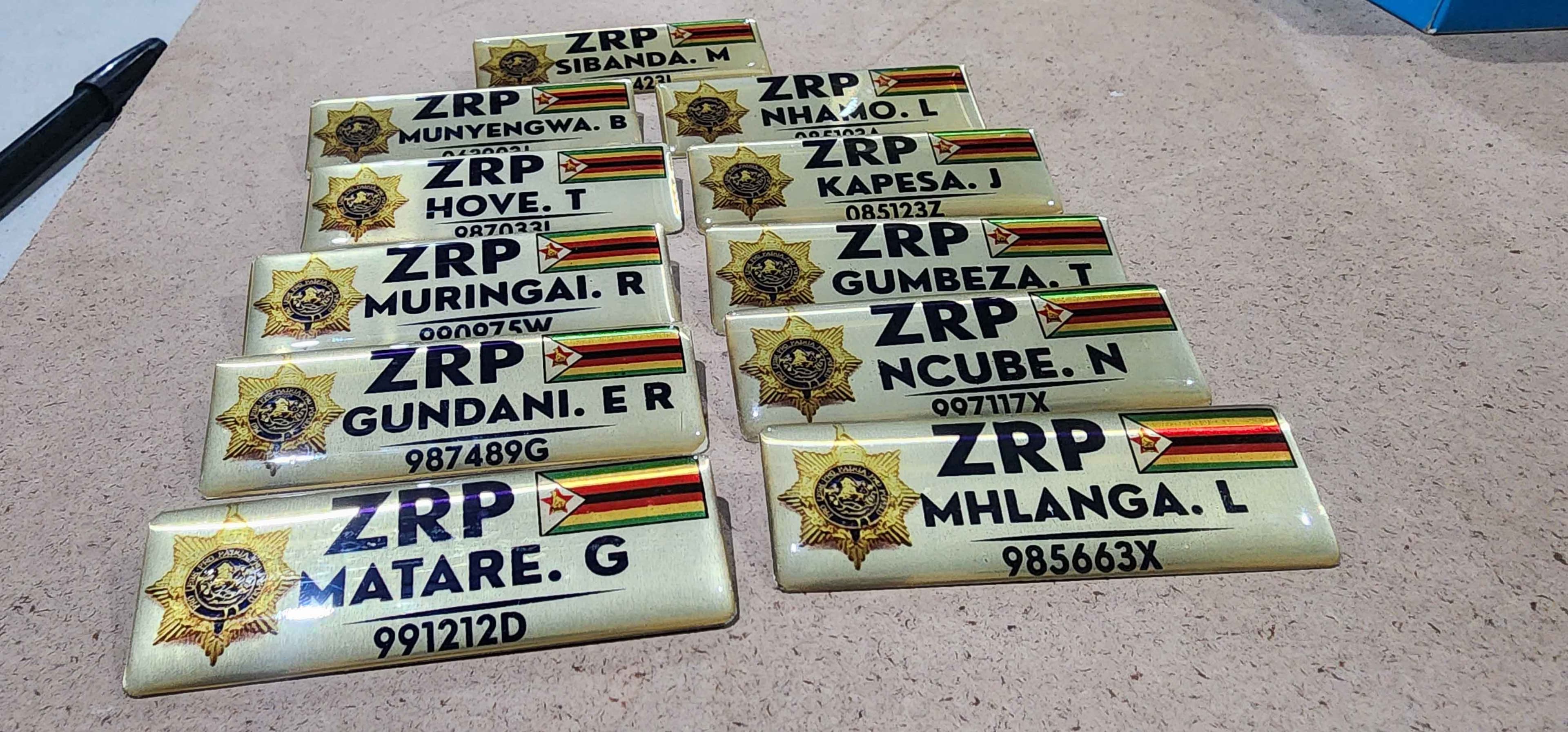 A set of uniformed service name badges showing an emblem, surname and force number